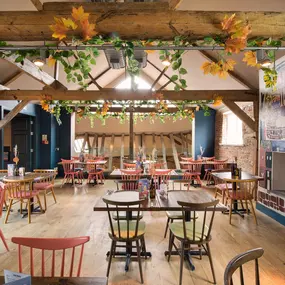 Zizzi Farnham, cozy interior with vibrant murals and hanging orange foliage.