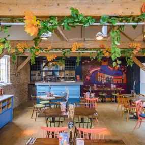 Zizzi Farnham, cozy interior with vibrant murals and hanging orange foliage.
