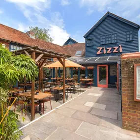 Zizzi Farnham, tucked-away courtyard with covered outdoor terrace and glowing sign.