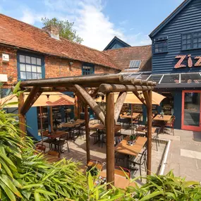 Zizzi Farnham, tucked-away courtyard with covered outdoor terrace and glowing sign.