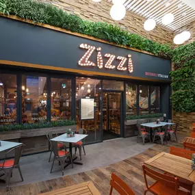 Exterior entrance of Zizzi Hull with greenery wall and outdoor seating.