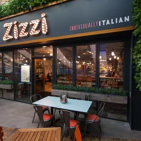 Exterior entrance of Zizzi Hull with greenery wall and outdoor seating.