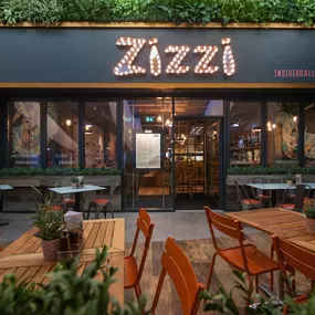 Exterior entrance of Zizzi Hull with greenery wall and outdoor seating.