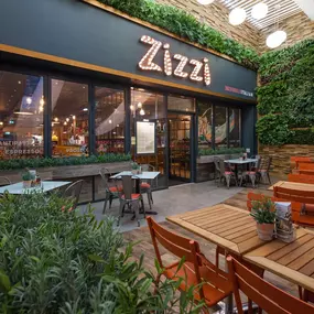 Exterior entrance of Zizzi Hull with greenery wall and outdoor seating.