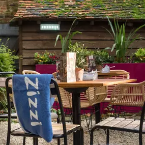 Zizzi Canterbury garden area with tables and chairs to enjoy the summers day surrounded by vibrant foliage.