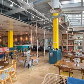 Cardiff Mermaid Quay, waterfront tables with panoramic bay views and lively mural with booth seating and pastel accents.