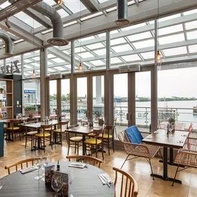 Cardiff Mermaid Quay, waterfront tables with panoramic bay views and lively mural with booth seating and pastel accents.