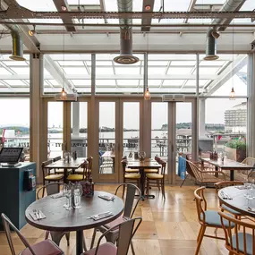 Cardiff Mermaid Quay, waterfront tables with panoramic bay views and lively mural with booth seating and pastel accents.
