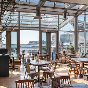 Cardiff Mermaid Quay, waterfront tables with panoramic bay views and lively mural with booth seating and pastel accents.