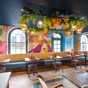Zizzi Hereford, vibrant dining with hanging ceiling foliage and warm lighting.