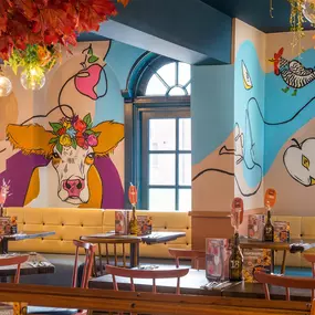 Zizzi Hereford, vibrant dining with hanging ceiling foliage and warm lighting.