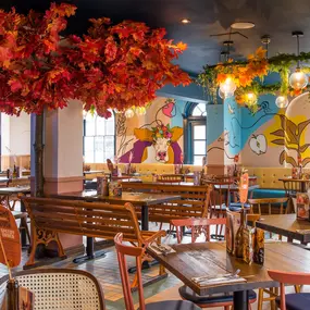 Zizzi Hereford, vibrant dining with hanging ceiling foliage and warm lighting.