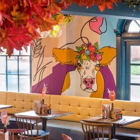 Zizzi Hereford, vibrant dining with hanging ceiling foliage and warm lighting.