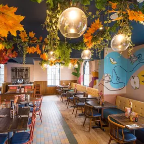 Zizzi Hereford, vibrant dining with hanging ceiling foliage and warm lighting.