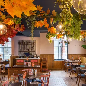 Zizzi Hereford, vibrant dining with hanging ceiling foliage and warm lighting.