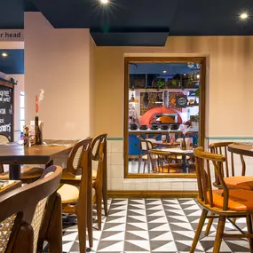 Zizzi Hereford, vibrant dining with hanging ceiling foliage and warm lighting.