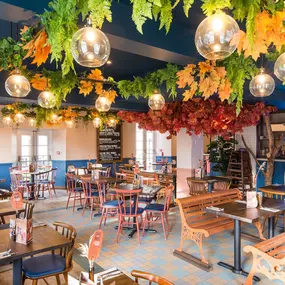 Zizzi Hereford, vibrant dining with hanging ceiling foliage and warm lighting.