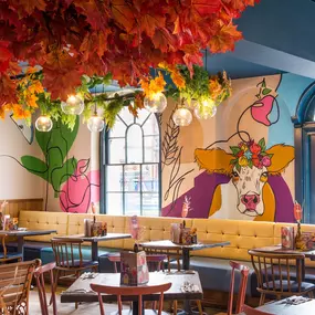 Zizzi Hereford, vibrant dining with hanging ceiling foliage and warm lighting.