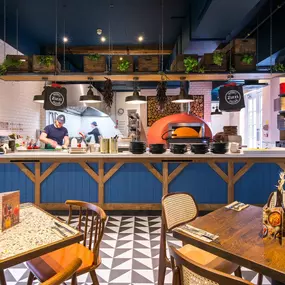 Zizzi Hereford, vibrant dining with hanging ceiling foliage and warm lighting.