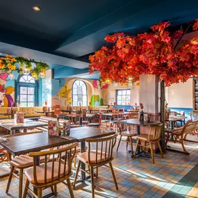 Zizzi Hereford, vibrant dining with hanging ceiling foliage and warm lighting.