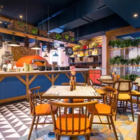 Zizzi Hereford, vibrant dining with hanging ceiling foliage and warm lighting.