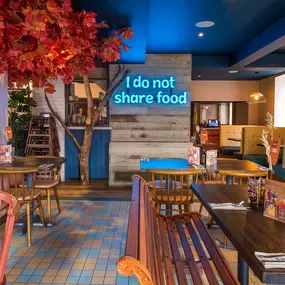 Zizzi Hereford, vibrant dining with hanging ceiling foliage and warm lighting.