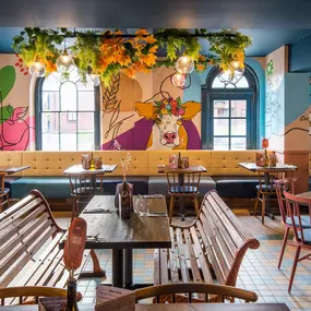 Zizzi Hereford, vibrant dining with hanging ceiling foliage and warm lighting.