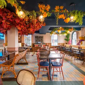 Zizzi Hereford, vibrant dining with hanging ceiling foliage and warm lighting.