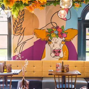Zizzi Hereford, vibrant dining with hanging ceiling foliage and warm lighting.