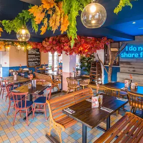 Zizzi Hereford, vibrant dining with hanging ceiling foliage and warm lighting.