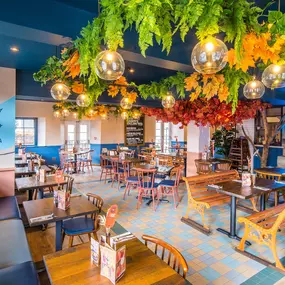 Zizzi Hereford, vibrant dining with hanging ceiling foliage and warm lighting.