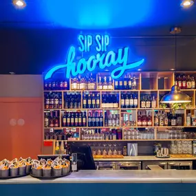 Zizzi Chiswick's bar and decor neon sign saying 'sip sip hooray'.
