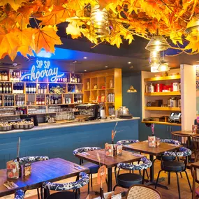 Zizzi Chiswick, showcases wooden tables and chairs beneath decorative copper foliage suspended from the ceiling.