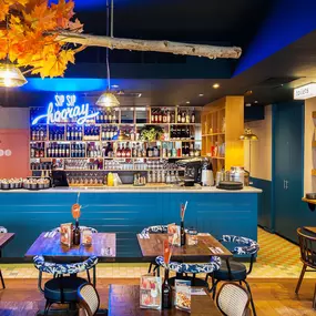 Zizzi Chiswick, showcases wooden tables and chairs beneath decorative copper foliage suspended from the ceiling.