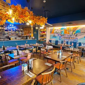 Zizzi Chiswick, showcases wooden tables and chairs beneath decorative copper foliage suspended from the ceiling.