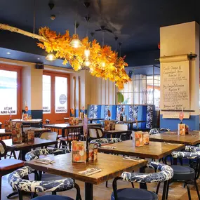 Zizzi Chiswick, showcases wooden tables and chairs beneath decorative copper foliage suspended from the ceiling.