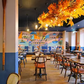 Zizzi Chiswick, showcases wooden tables and chairs beneath decorative copper foliage suspended from the ceiling.