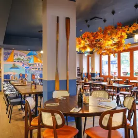 Zizzi Chiswick, showcases wooden tables and chairs beneath decorative copper foliage suspended from the ceiling.