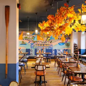 Zizzi Chiswick, showcases wooden tables and chairs beneath decorative copper foliage suspended from the ceiling.