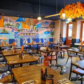 Zizzi Chiswick, showcases wooden tables and chairs beneath decorative copper foliage suspended from the ceiling.