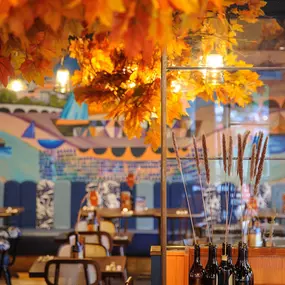 Zizzi Chiswick, showcases wooden tables and chairs beneath decorative copper foliage suspended from the ceiling.