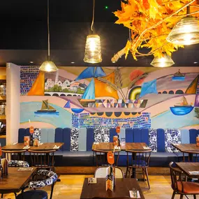 Zizzi Chiswick, showcases wooden tables and chairs beneath decorative copper foliage suspended from the ceiling.