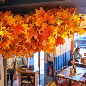 Zizzi Chiswick, showcases wooden tables and chairs beneath decorative copper foliage suspended from the ceiling.