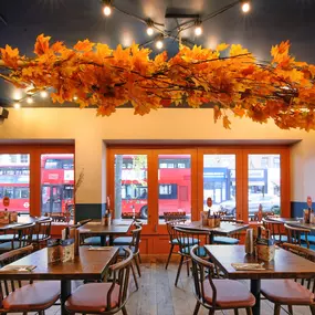Zizzi Chiswick, showcases wooden tables and chairs beneath decorative copper foliage suspended from the ceiling.