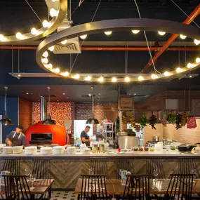 Zizzi Coventry, vibrant dining space with high ceilings and natural light, hanging decor and artistic wall art.