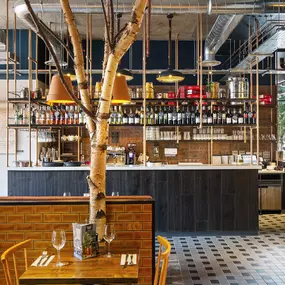 Zizzi Coventry, vibrant dining space with high ceilings and natural light, hanging decor and artistic wall art.