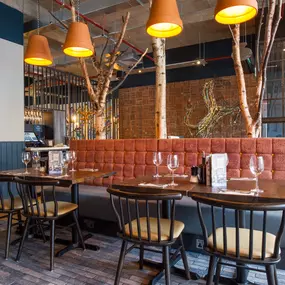 Zizzi Coventry, vibrant dining space with high ceilings and natural light, hanging decor and artistic wall art.