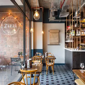 Zizzi Coventry, vibrant dining space with high ceilings and natural light, hanging decor and artistic wall art.