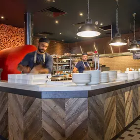 Zizzi Coventry, vibrant dining space with high ceilings and natural light, hanging decor and artistic wall art.