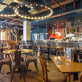 Zizzi Coventry, vibrant dining space with high ceilings and natural light, hanging decor and artistic wall art.